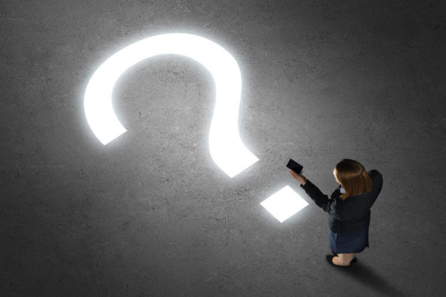 Woman holding smartphone in front of illuminated question mark