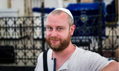 jewish man wearing yarmulke inside of a synagogue looking into camera