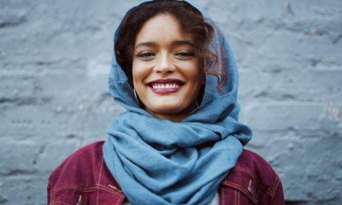 muslim woman wearing blue hijab smiles while looking into camera