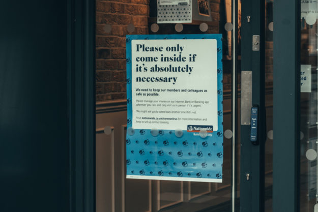Sign reading "Please only come inside if it's absolutely necessary" in business window
