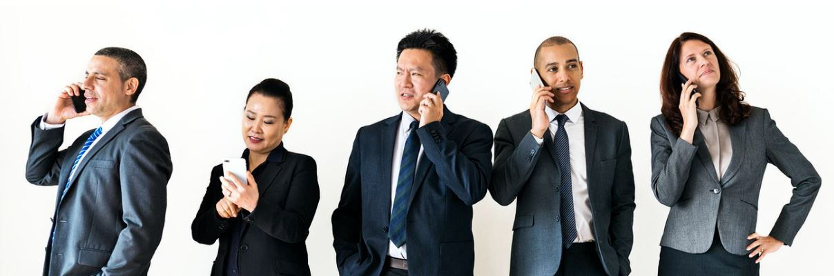 Five businesspeople standing next to each other talking on their cell phones against a white background