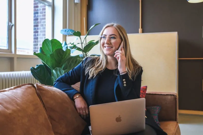 Blonde woman in blazer talking on phone in modern office