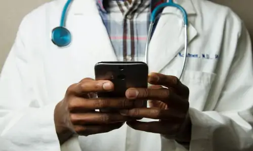 African-American doctor holding smartphone with both hands