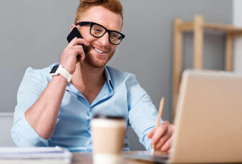 man talking on smartphone while working in home office
