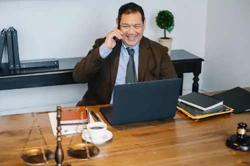 lawyer talking on cell phone while at laptop in office