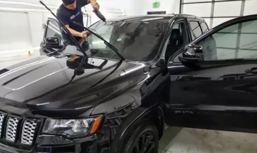 Worker applying tint to windshield of Jeep Cherokee