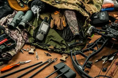 Collection of bow hunting equipment spread out on camouflage jacket 