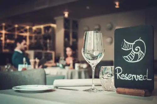 reserved sign on table at restaurant with dining couple in background