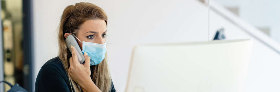 Receptionist in face mask talking on phone