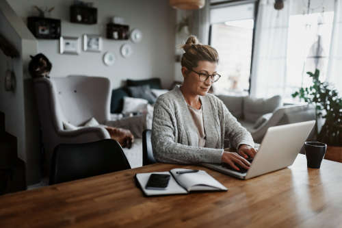 woman working from home at long wooden table with furniture in background