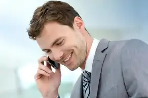 white man in grey suit talking on smartphone