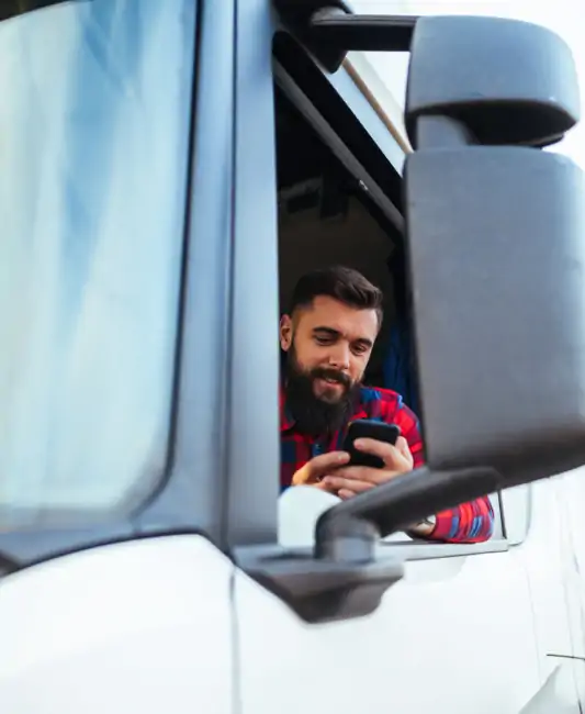 driver in semi truck holding and looking at smartphone