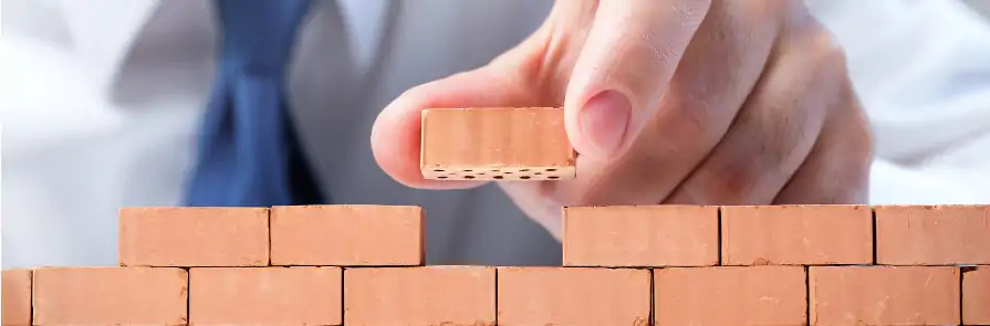man placing miniature brick on model wall