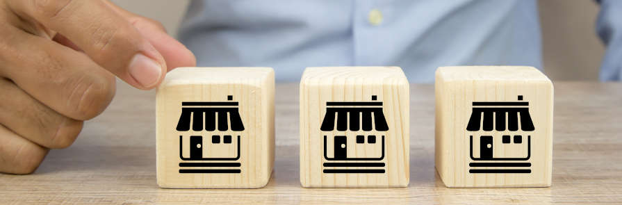 man's hand reaching for one of three wooden blocks stamped with business icon on them