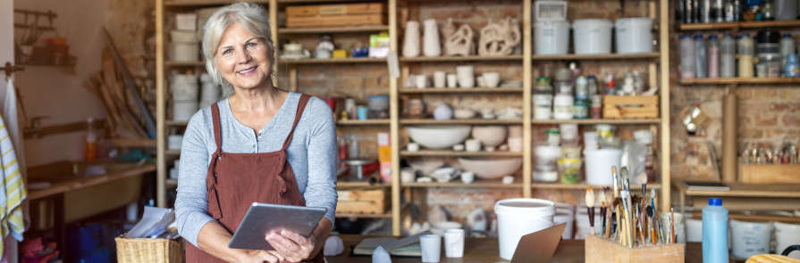 woman smiling in art studio with tablet computer in hands