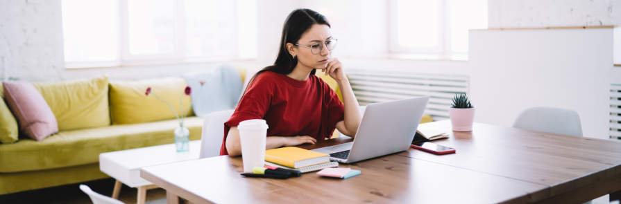 woman sitting on her laptop at kitchen table while working from home