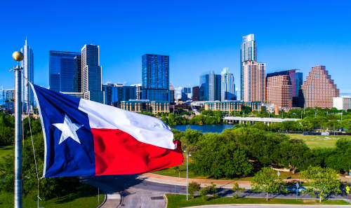 Texas state flag waving in front of Austin city skyline